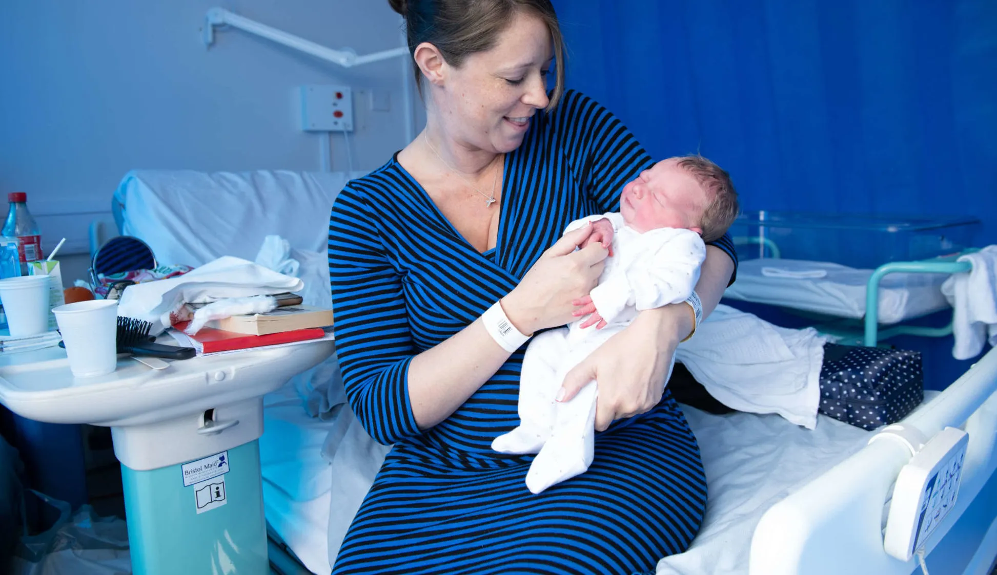 Mother holding baby in arms and smiling in maternity ward