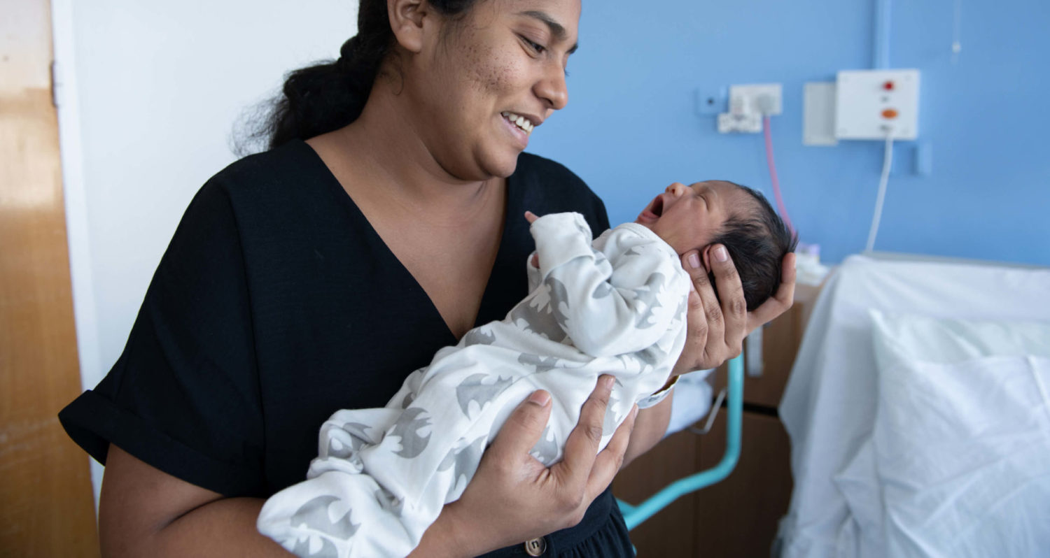 A new mother smiles at her newborn infant