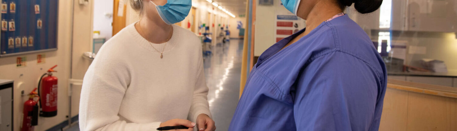 Two healthcare professionals laugh in the hallway of a maternity service