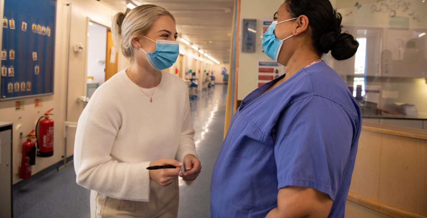 Two healthcare professionals laugh in the hallway of a maternity service