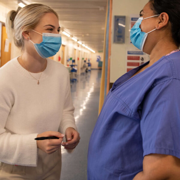 Two healthcare professionals laugh in the hallway of a maternity service