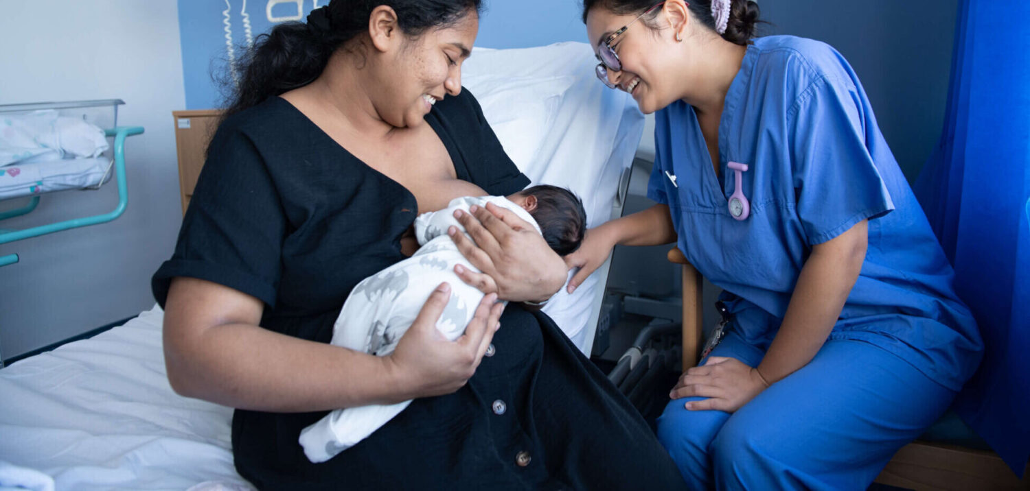 A new mother breastfeeds her infant with the support of a healthcare professional on the maternity unit.