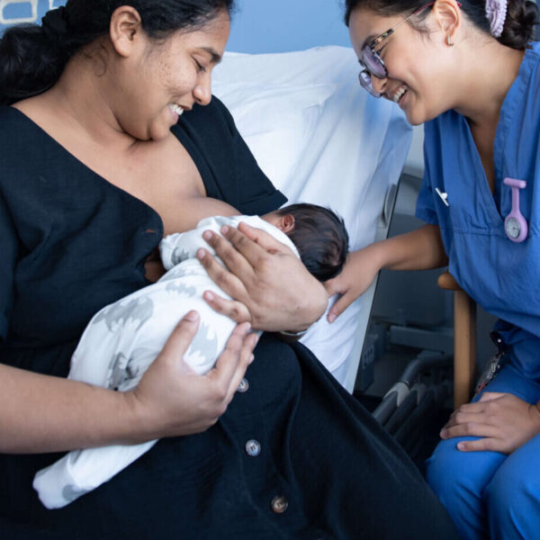 A new mother breastfeeds her infant with the support of a healthcare professional on the maternity unit.