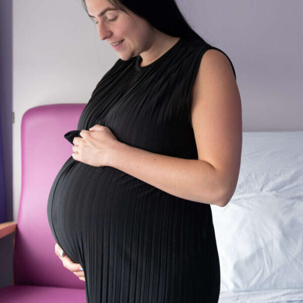 A pregnant mother-to-be smiles at her bump in the maternity unit.