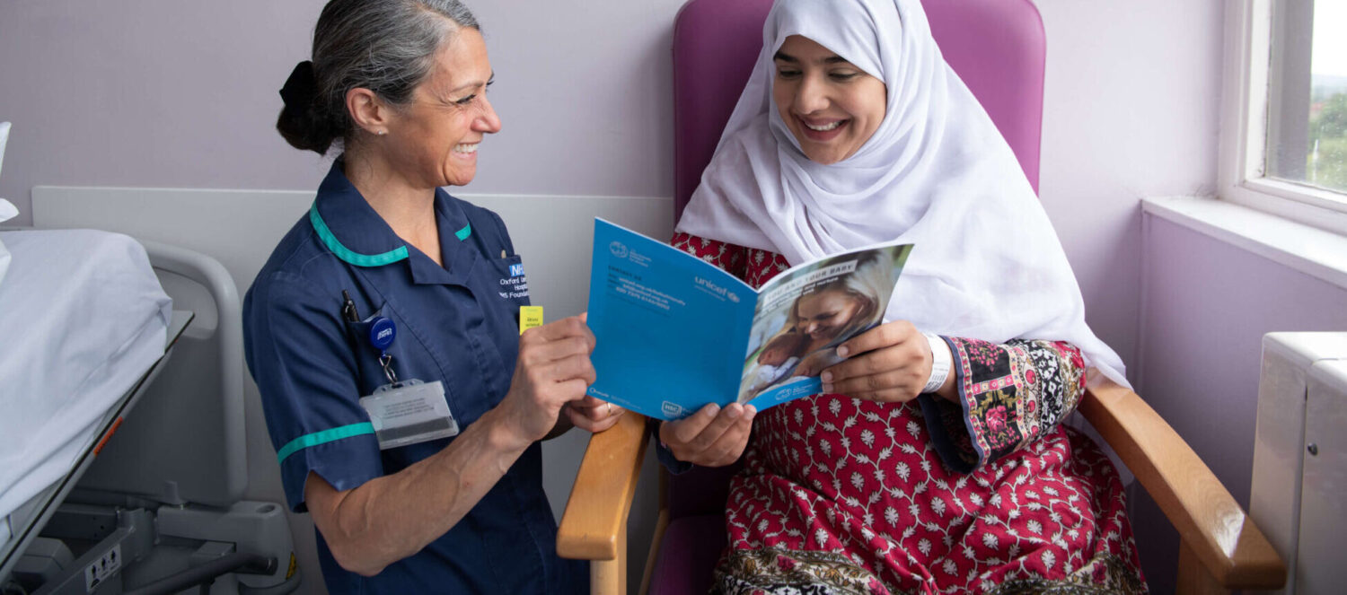 An infant feeding healthcare professional supports a pregnant woman with guidance produced by the UNICEF UK Baby Friendly Initiative