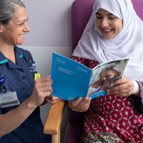 An infant feeding healthcare professional supports a pregnant woman with guidance produced by the UNICEF UK Baby Friendly Initiative