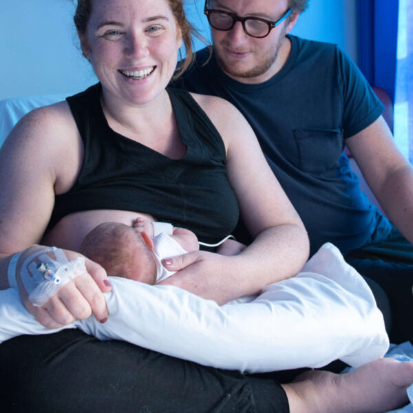 Smiling mum breastfeeding with partner