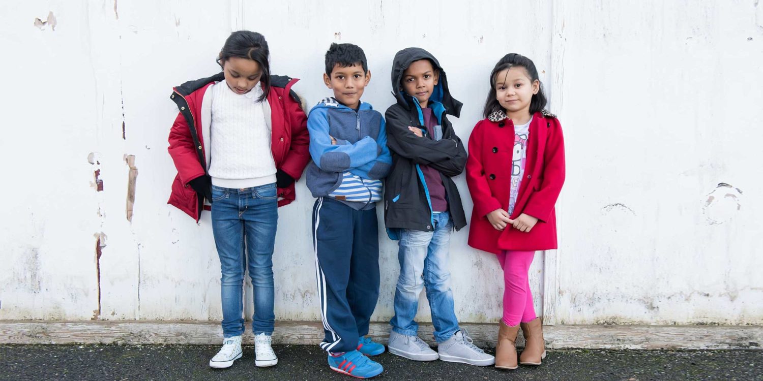 Four children stood against a wall