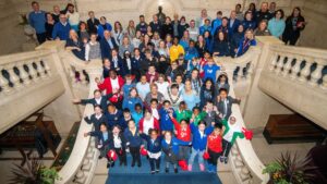 A group of children and adults stand cheering on a staircase