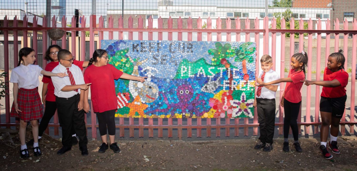 A group of pupils pointing at their 'Keep our sea plastic free' display