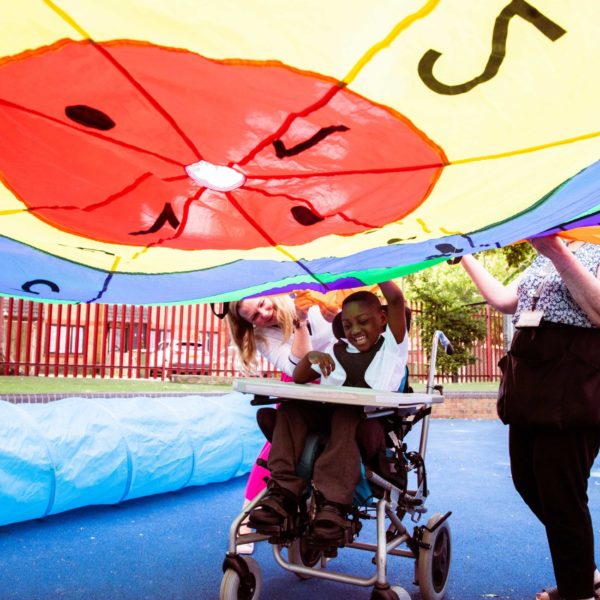 A boy in a wheelchair playing the parachute playground game