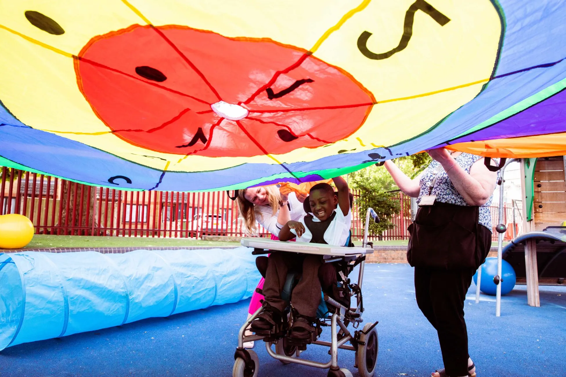 A boy in a wheelchair playing the parachute playground game