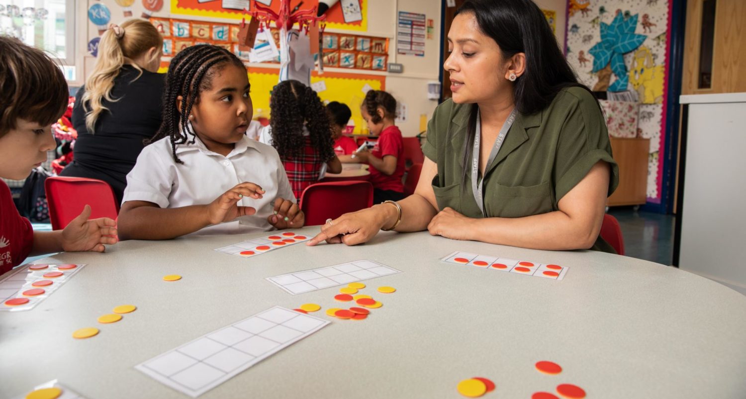 A teacher supporting two young pupils during an activity