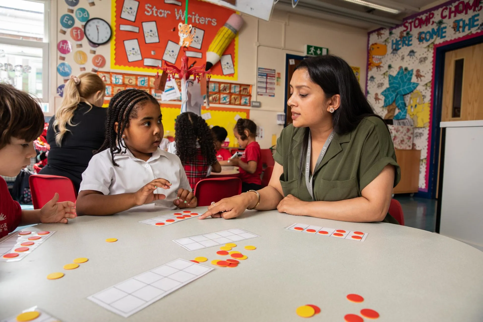 A teacher supporting two young pupils during an activity