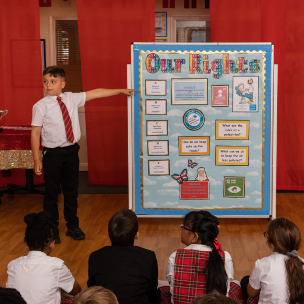 A boy at school standing next to a display about children's rights