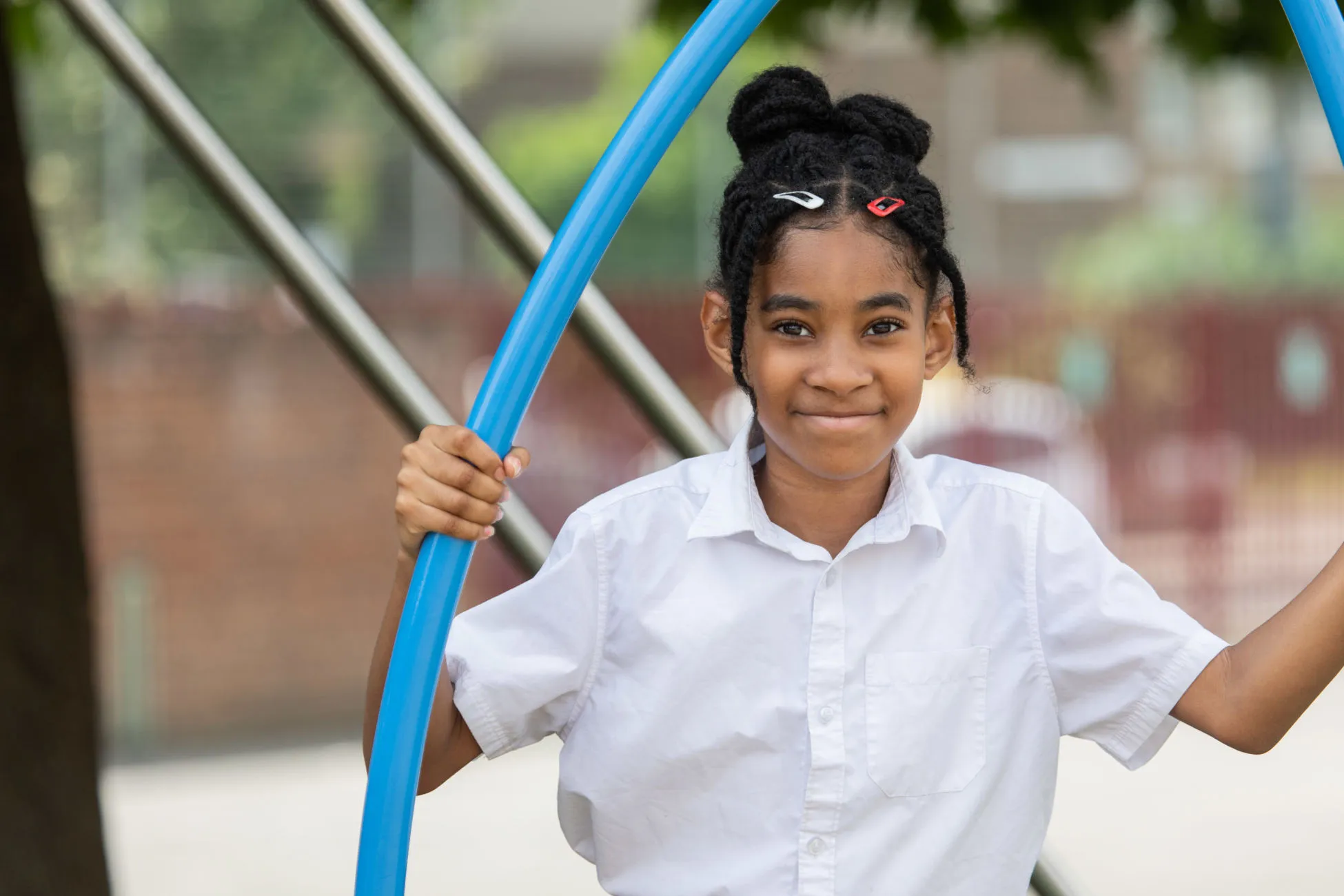 A girl smiling at a camera while playing at a playground at school