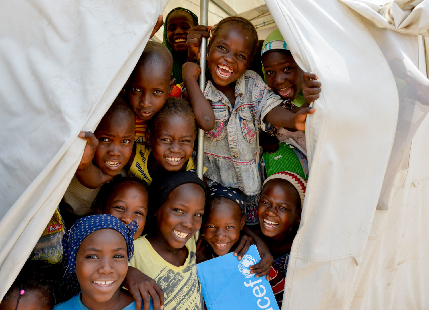 Children smiling in a Unicef-supported tent in Nigeria. Unicef 2015 Rich