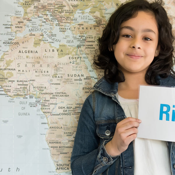 A child at school holds up a sign showing that we all have rights. All of our work is based on the UNCRC. UNICEF/2016/Fields