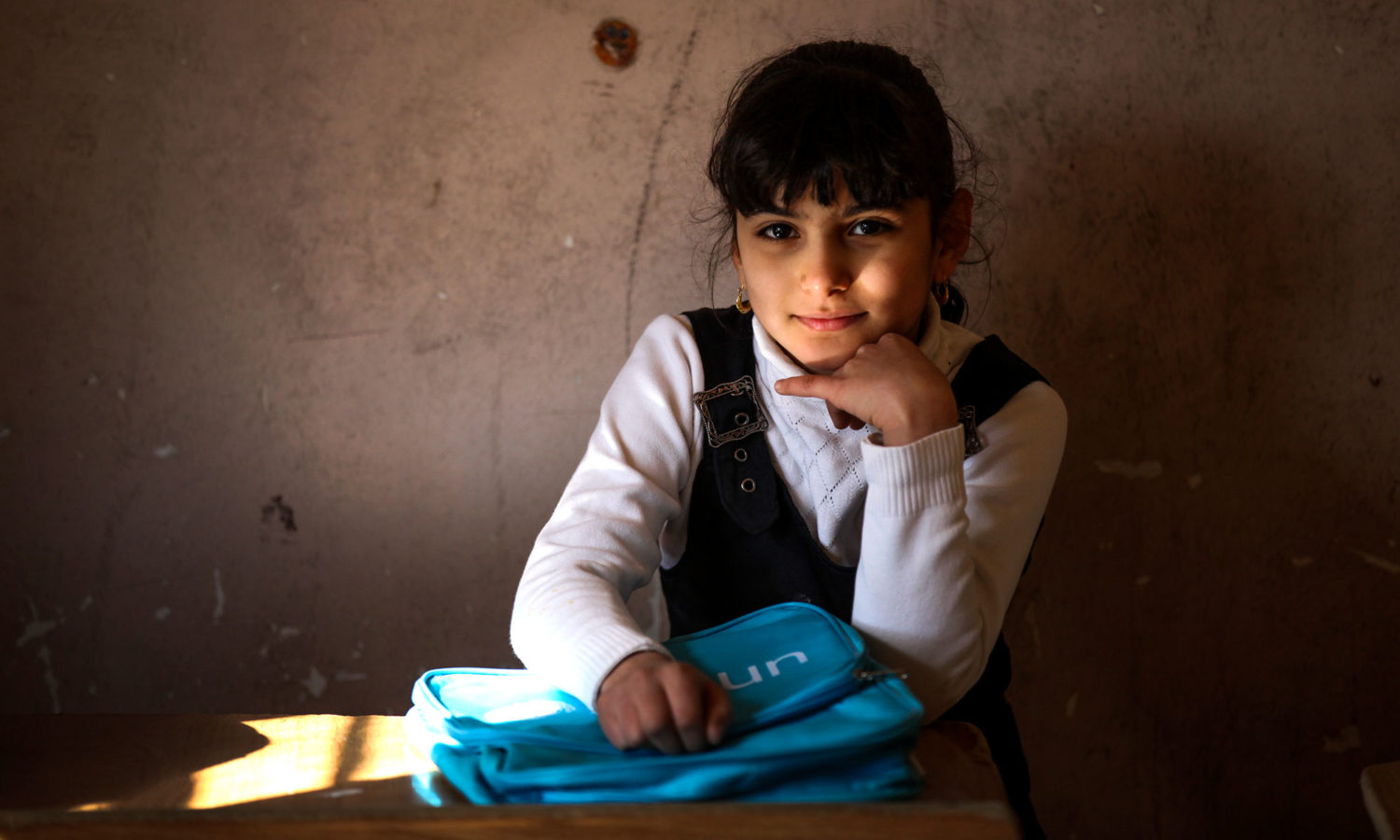 Janna, 8, from Baghdad, sits in a classroom with her new Unicef school bag after a school supply distribution for children from five schools in Baghdad's Al-Amiriyah District.