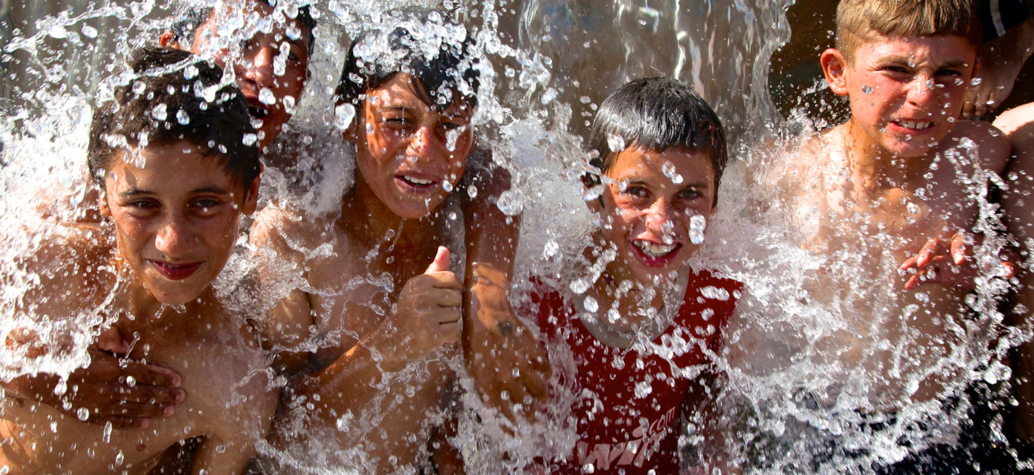 Group of children splashing in water in Dohuk Governorate.