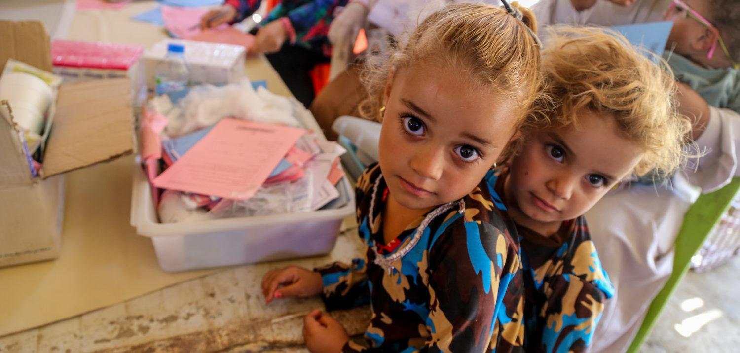 Two girls wait in line at a temporary medical centre in Iraq.