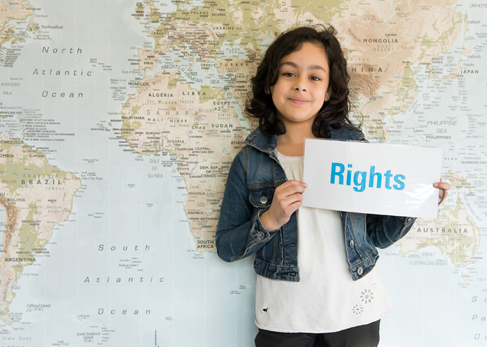 A pupil pupil from Bangabandhu Primary School in Tower Hamlets, London, stands in front of a world map. © Unicef UK/14/ Susannah Fields