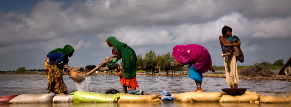 On 15 September, a family washes clothing in the flood waters near their camp, in the city of Digri, in Sindh Province. They are standing on sandbags at the edge of the rising water. Unicef/Pakistan 2011/Page