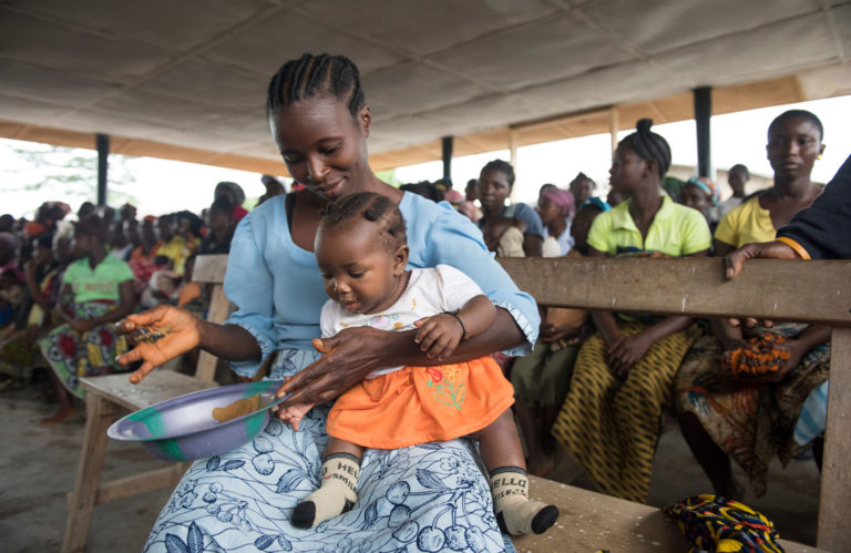 Yassah feeding Watta, her 6-month old daughter, a nutritious porridge prepared in front of other mothers. A part of Unicef Liberia's Nutrition Programme, these cooking demonstrations help to tackle the country's widespread malnutrition crisis. Photo: Unicef/Maule-ffinch