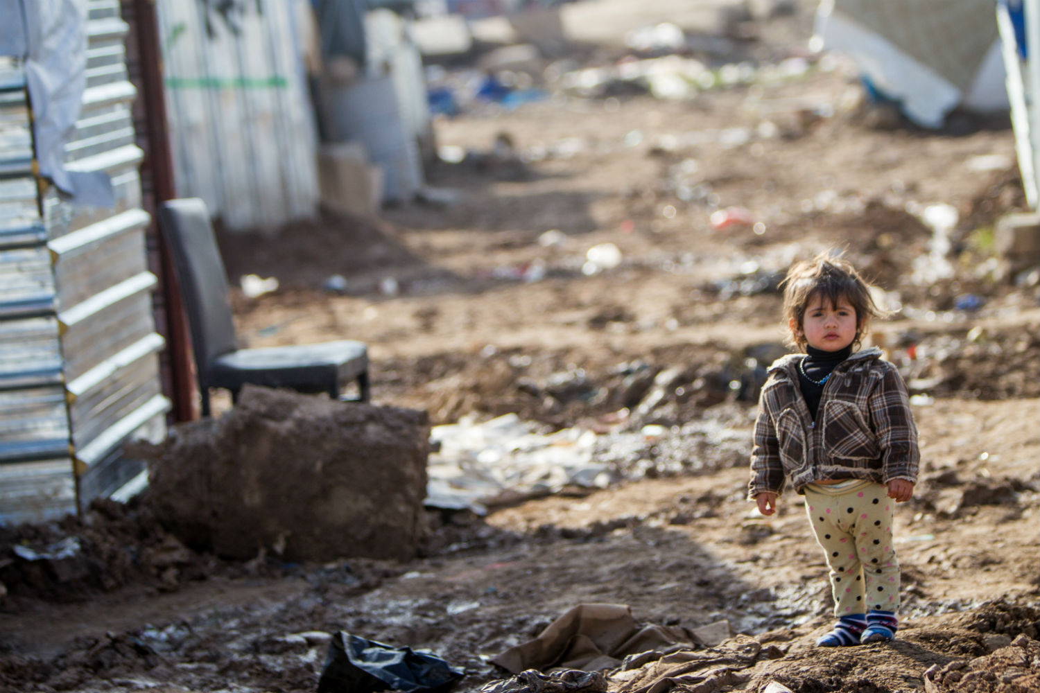 Hakim's little sister Amira walks shoeless among the dirt and frozen puddles to the outside toilet. © Unicef/2014//Schernbrucker