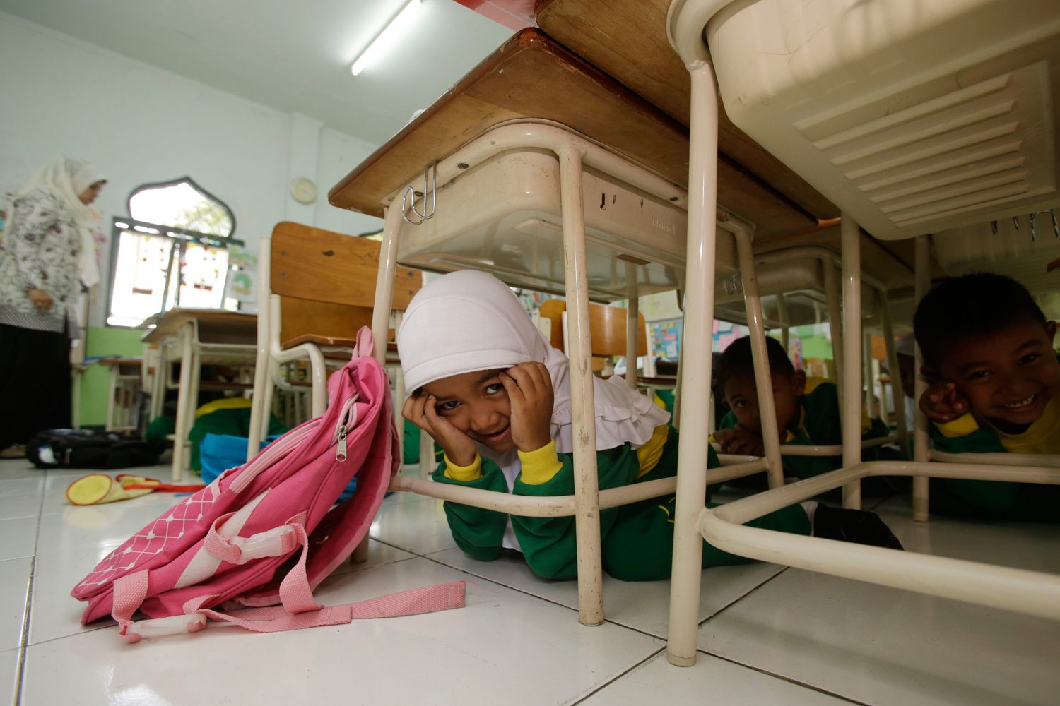 Students sit under a table during an earthquake drill at a primary school in Indonesia, which was struck by the deadly Boxing Day Tsunami in 2004. Photo: Unicef/2014/Achmadi
