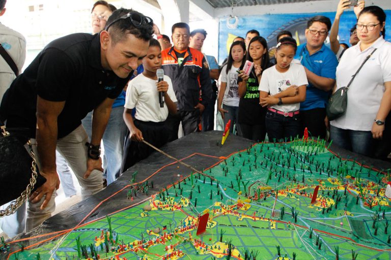 Unicef Philippines Goodwill Ambassador Gary Valenciano listens to Lyn Lyn, 10, as she explains the hazards and vulnerabilities in her village through Participatory 3D Mapping. Photo: Unicef Philippines/2015/Dimatatac