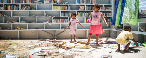 Two young girls standing in destroyed library.