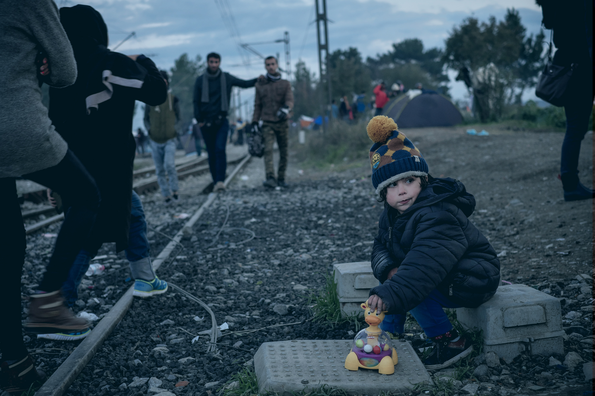 On 26 November, Hussein Marge, 3-and-a-half years old, plays with a toy by railway tracks in a temporary camp near town of Idomeni, close to the border with the former Yugoslav Republic of Macedonia. Hussein and his family, who are from Lebanon’s capital Beirut, are hoping to cross into the former Yugoslav Republic of Macedonia – where the Government has begun restricting the flow of refugees and migrants on the move, and is allowing only Syrians, Iraqis and Afghans to continue their journey. About 1,300 refugees protested the Government’s decision to deny entry to people not from those three countries. Refugees and migrants flows into Europe are at an unprecedented high. By end November, over 870,000 refugees and migrants had arrived by sea in Europe since the beginning of the year. More than one in five refugees and migrants reaching Europe is a child, and children make up an estimated one-quarter of the 730,000 sea arrivals in Greece and of flows heading towards Western and Northern Europe through the former Yugoslav Republic of Macedonia, Serbia, Croatia and Slovenia so far this year. The main nationalities of refugees and migrants include Syrians, Afghans and Iraqis. Recent restrictions imposed by governments at several border crossings in the Balkans is creating additional hardships and challenges for refugee and migrants, including leaving some stranded at various crossing points, creating tensions and protests at border crossings, or forcing others to take further risks by taking dangerous smuggling routes to reach safety. UNICEF, together with partners UNHCR and IOM, is supporting child-friendly spaces in reception centres at border crossings along the Balkan routes, mobilizing for winter and working with governments to strengthen child protection systems for all children, including refugee and migrant children. UNICEF is also monitoring and providing assistance with partners at these points, and is providing blankets, winter clothing and other key items to meet basic needs. Unicef/2015/Gilbertson VII
