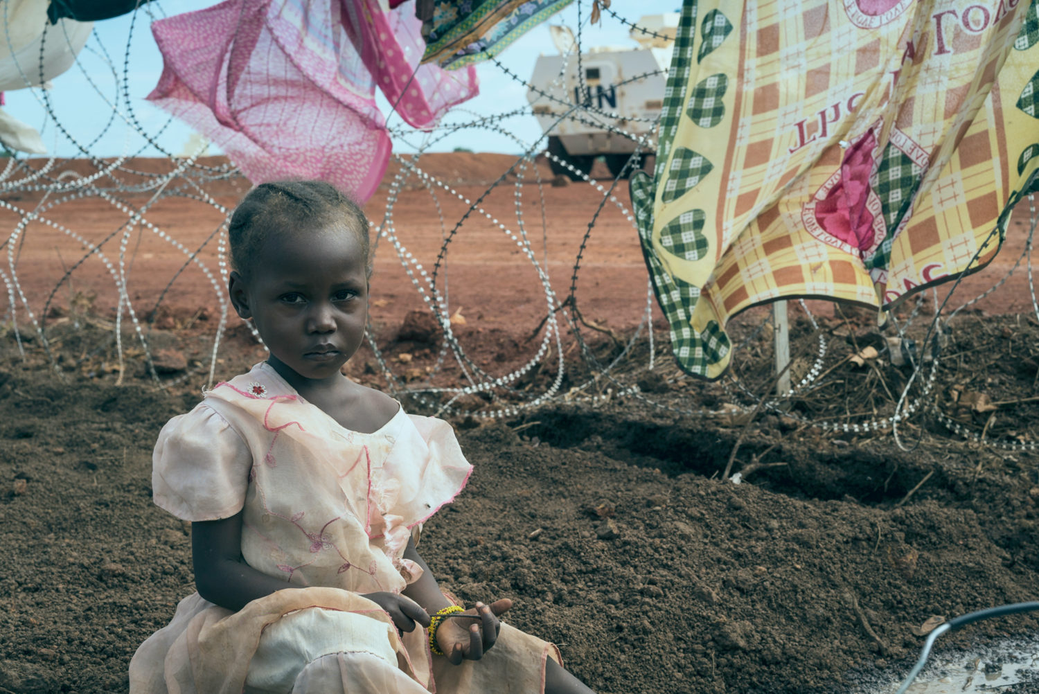 Niema, 3, sits on the ground while her mother washes clothes in a Protection of Civilians Site in South Sudan. Unicef/2016/Ohanesian