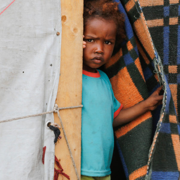 An internally displaced child stands at the entrance to his family’s shelter in the Tharawan IDP camp in the outskirts of Sana’a, Yemen.