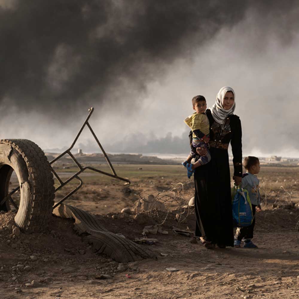 A newly displaced woman walks with two children at a check point in Qayyara, south of Mosul on October 31, 2016. Unicef/2016/Romenzi