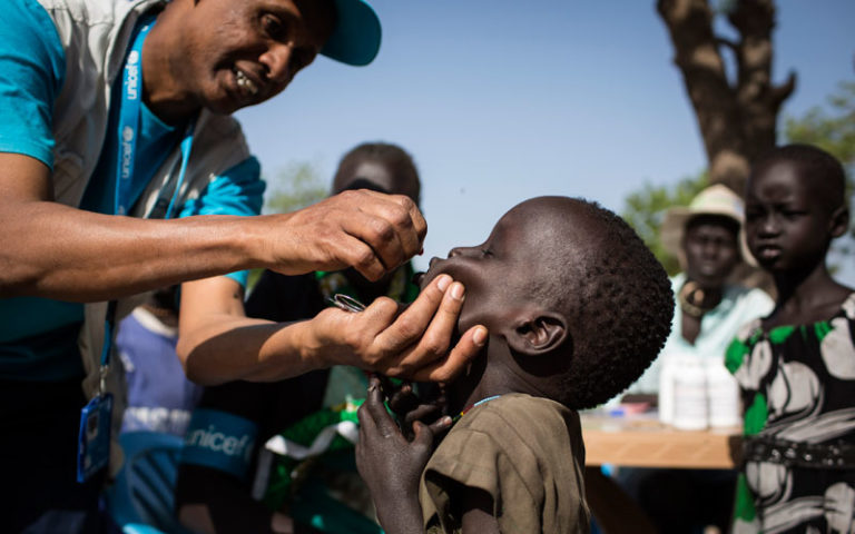 Unicef Nutrition Specialist, Kibrom Tesfaselassie gives a child a vitamin supplement during a Rapid Response Mechanism (RRM) mission in Thonyor, Leer County, South Sudan. Photo: Unicef/Modola