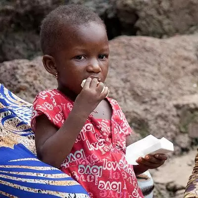 A child eats a nutritious high-energy biscuit, a simple way to guard against malnutrition in an emergency.