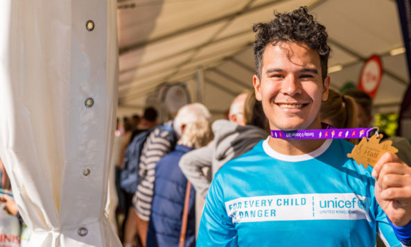 Unicef runner Guillermo holds up his medal after the 2017 Royal Parks Half Marathon. Photo: Unicef/Tsang