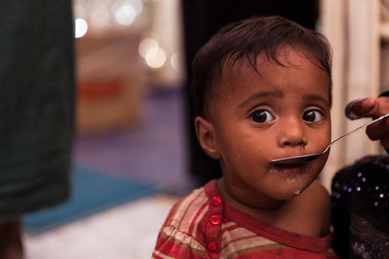 A Rohingya child receives emergency life-saving food