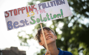 A boy holds up a placard saying "Stopping pollution is the best solution" Photo: Unicef/2018/Sutton-Hibbert