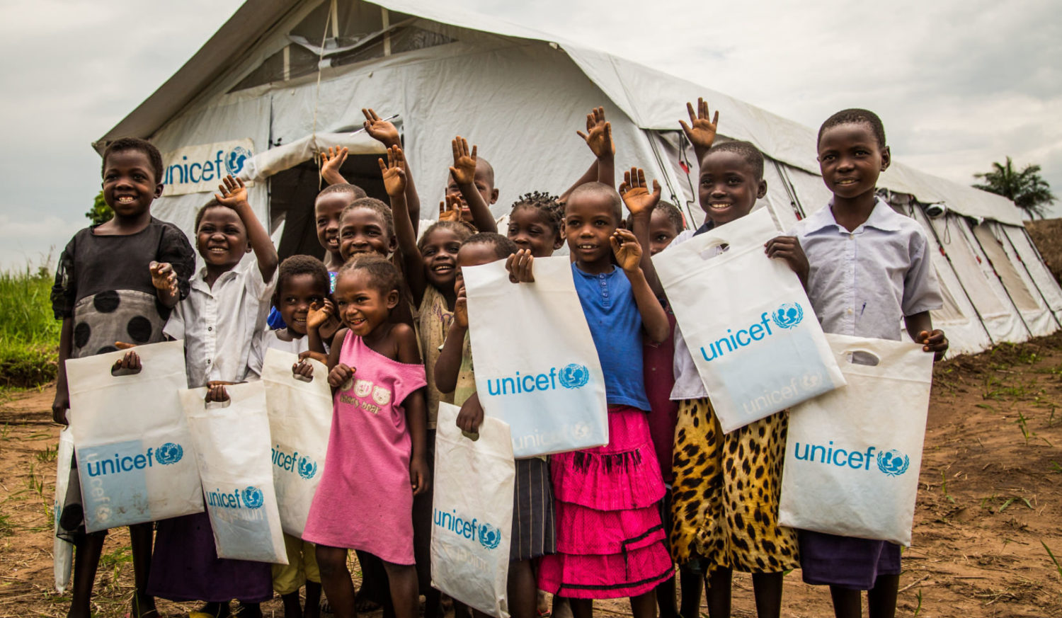 Students stand outside their temporary tent school setup by UNICEF, following a class in Mulombela village, Kasaï region, Democratic Republic of the Congo,