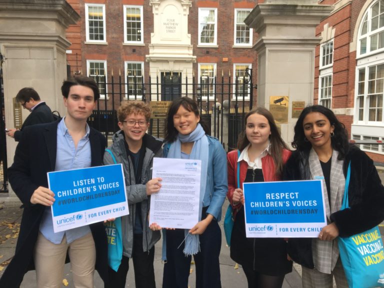 UNICEF UK Youth Advisory Board members stand in a group with messageboards about children's rights.