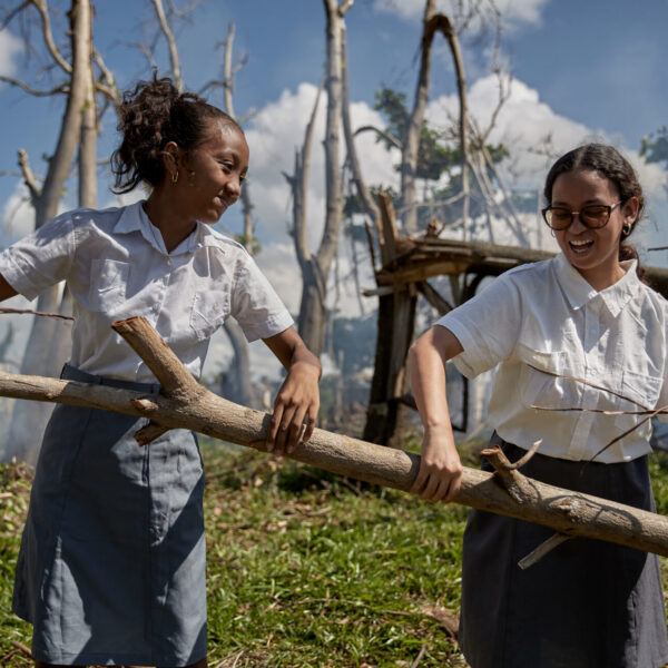 Tsito, 16 (left), and Liantsoa, 20, two sisters, take part in the clean-up effort, carrying branches and debris within the school premises.