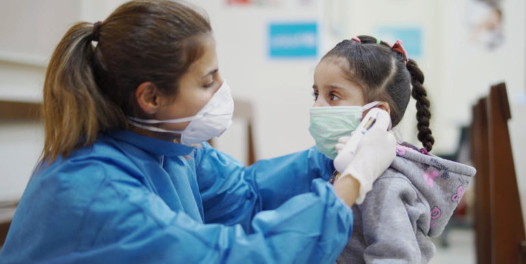 Girl being assisted with wearing a mask