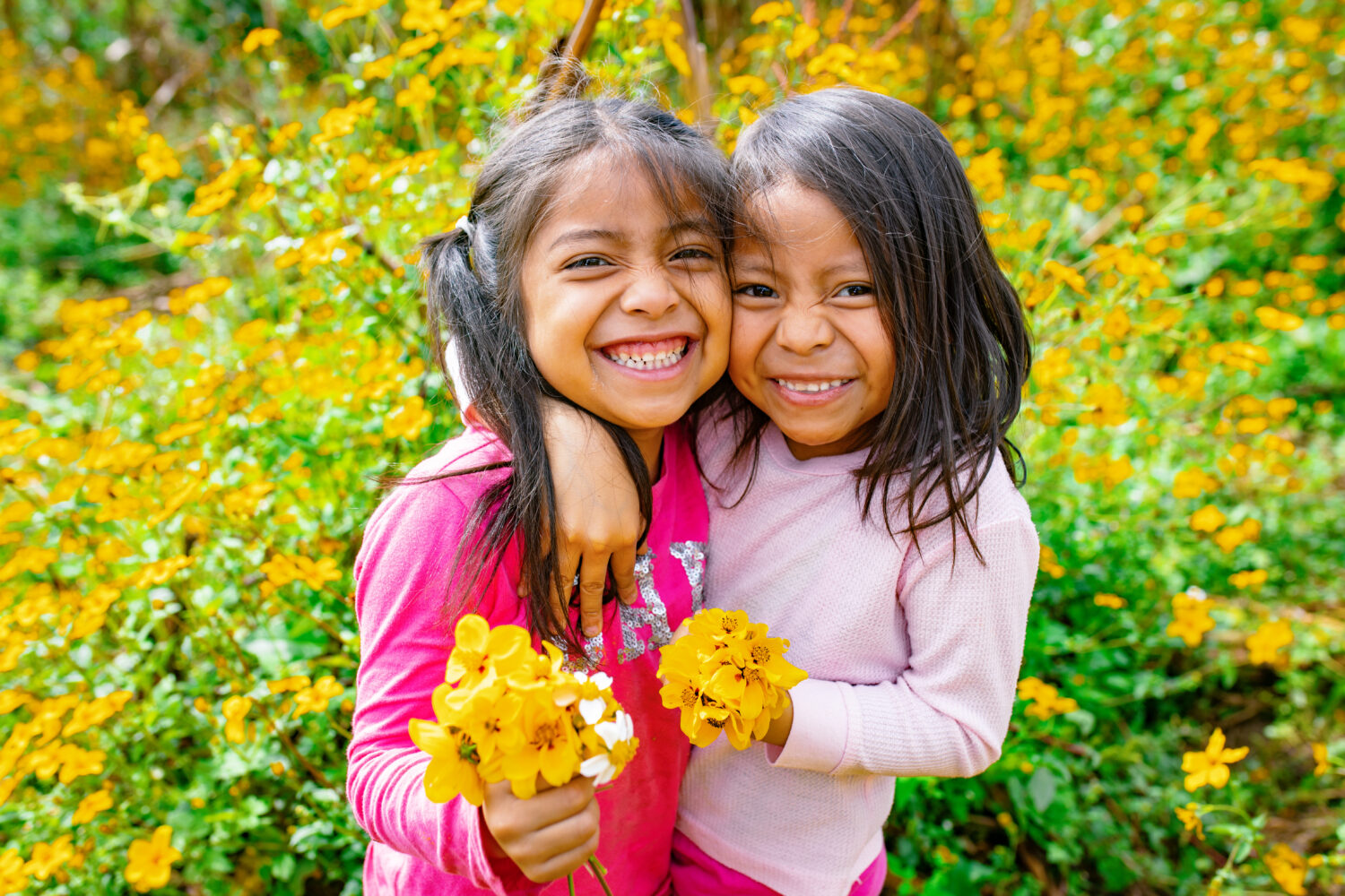 Two children smiling together in a field at the back of their house in Olintepeque, Quetzaltenango, Guatemala.