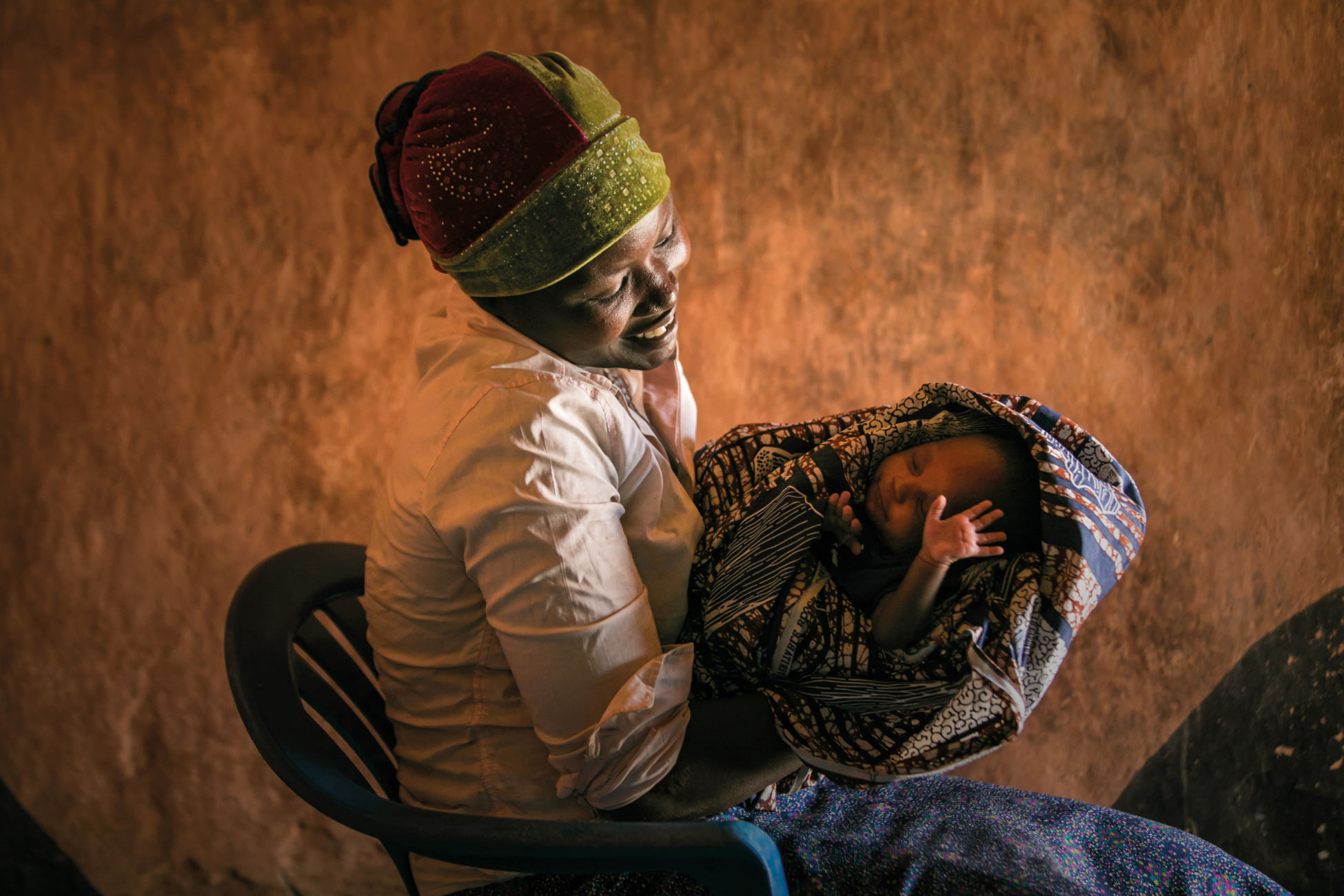 A woman smiling tenderly holding her newborn baby.