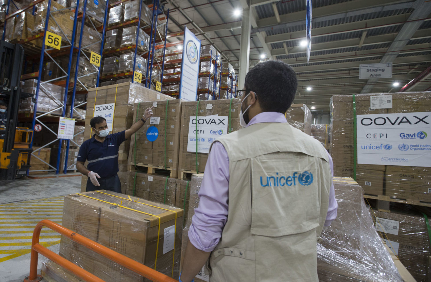 UNICEF colleagues work in a warehouse overseeing the distribution of boxes of auto-disable syringes and safety boxes