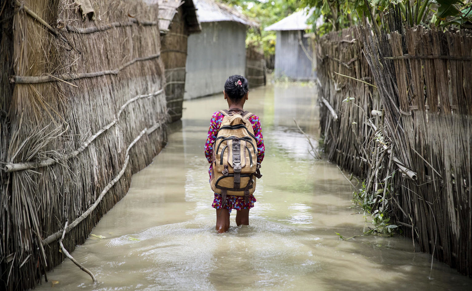 A child wades through water on her way to school in Bangladesh. © UNICEF/Akash