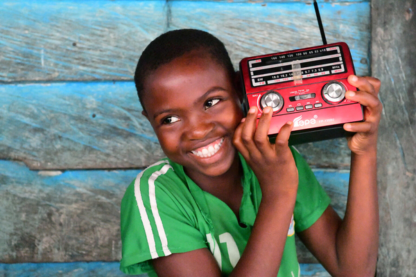 Child holding radio while listening to an education programme in Cameroon. UNICEF/Dejongh